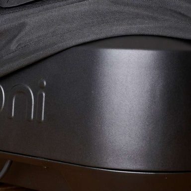 Ooni Volt Pizza Oven Cover close-up of the black woven hem draped over the matte dark gray oven body with the embossed ooni wordmark below it.