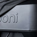 Ooni Volt Pizza Oven Cover close-up of the fabric edge lifted off the oven front, showing the embossed ooni wordmark and the base of the oven below.