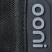 Ooni Volt Pizza Oven Cover close-up of the stitched black woven edge beside the raised gray ooni badge on the smooth dark panel.
