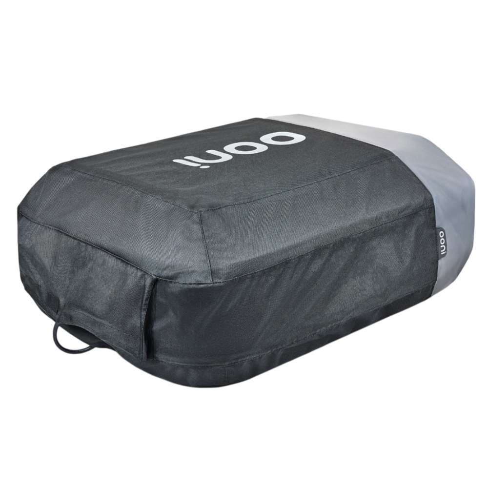 Ooni Volt Pizza Oven Cover fitted over the oven on a white background, angled to show the charcoal woven fabric, the white ooni logo across the top, and an elastic loop at the lower corner.
