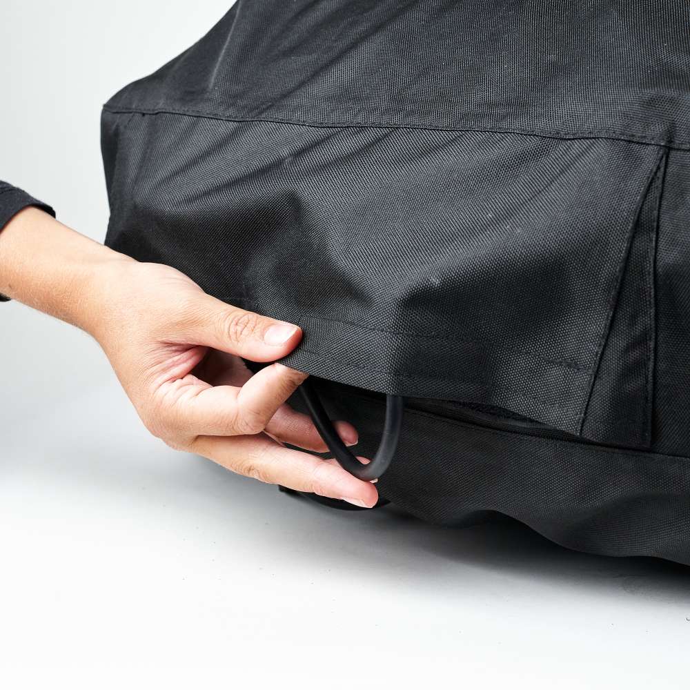 Ooni Volt Pizza Oven Cover with a hand pulling the elastic drawcord along the bottom hem to tighten it around the oven.