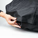 Ooni Volt Pizza Oven Cover with a hand pulling the elastic drawcord along the bottom hem to tighten it around the oven.