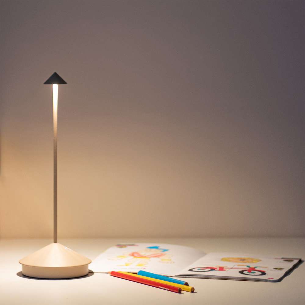 Sand Brown Crate & Barrel Pina Pro Metal Table Lamp by Zafferano America shown from an angle beside its induction charging base