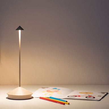 Sand Brown Crate & Barrel Pina Pro Metal Table Lamp by Zafferano America shown from an angle beside its induction charging base