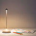 Sand Brown Crate & Barrel Pina Pro Metal Table Lamp by Zafferano America shown from an angle beside its induction charging base
