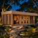 Illuminated wooden Sauna Largo 90 on a bright Texas evening with two adults relaxing inside beside a landscaped koi pond.