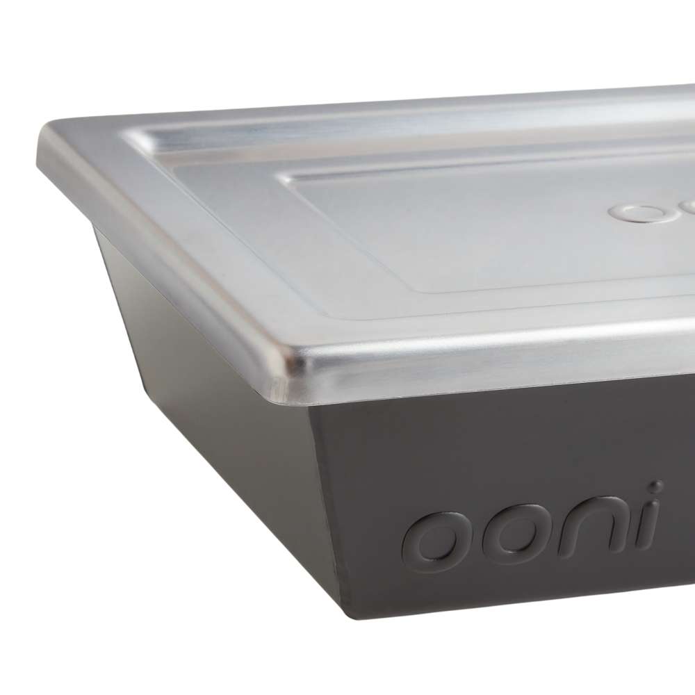Small Ooni Detroit Pizza Pan close-up of one corner where the brushed stainless steel lid overhangs the dark gray pan wall.