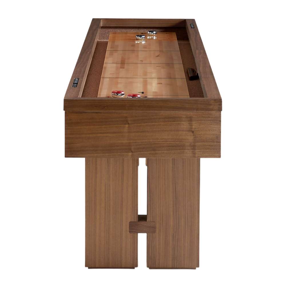 Walnut Crate & Barrel Shuffleboard seen end on against a white background, looking along the pale maple playfield to red and black pucks at the far end above the cabinet and two slab legs