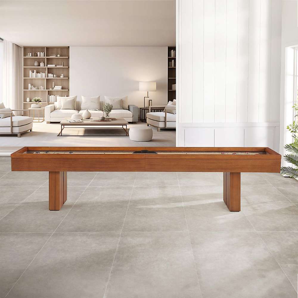 Walnut Crate & Barrel Shuffleboard seen from the side in an open living space with pale grey tile floors and a white panelled wall, with a cream sofa, bookshelves and a lamp in the room beyond