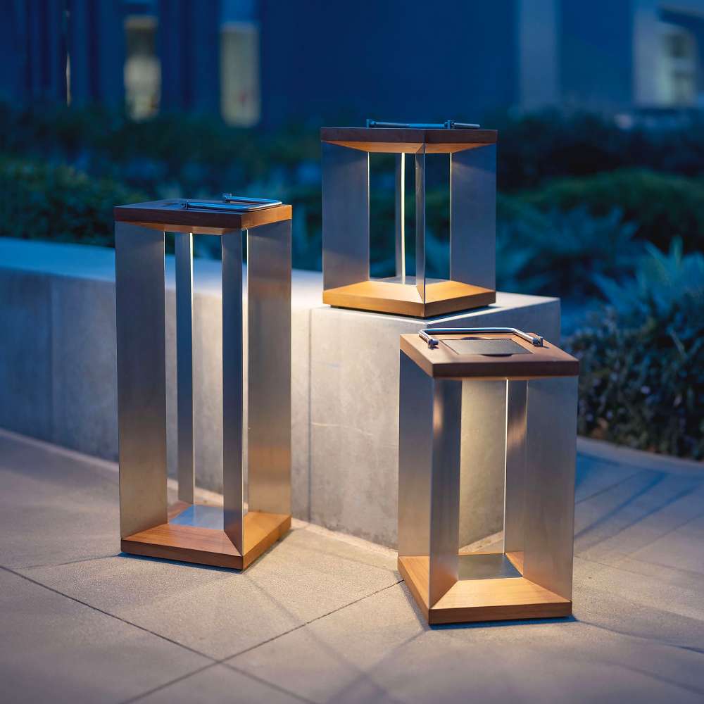Weathered Teak Crate & Barrel Blade Teak and Stainless Steel LED Solar Outdoor Lantern shown in a styled outdoor setting, a solar lantern with a metal carry handle