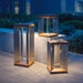 Weathered Teak Crate & Barrel Blade Teak and Stainless Steel LED Solar Outdoor Lantern shown in a styled outdoor setting, a solar lantern with a metal carry handle