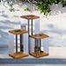 Weathered Teak Crate & Barrel Blade Teak and Stainless Steel LED Solar Outdoor Lantern shown in a styled outdoor setting, lit between its angled steel blades