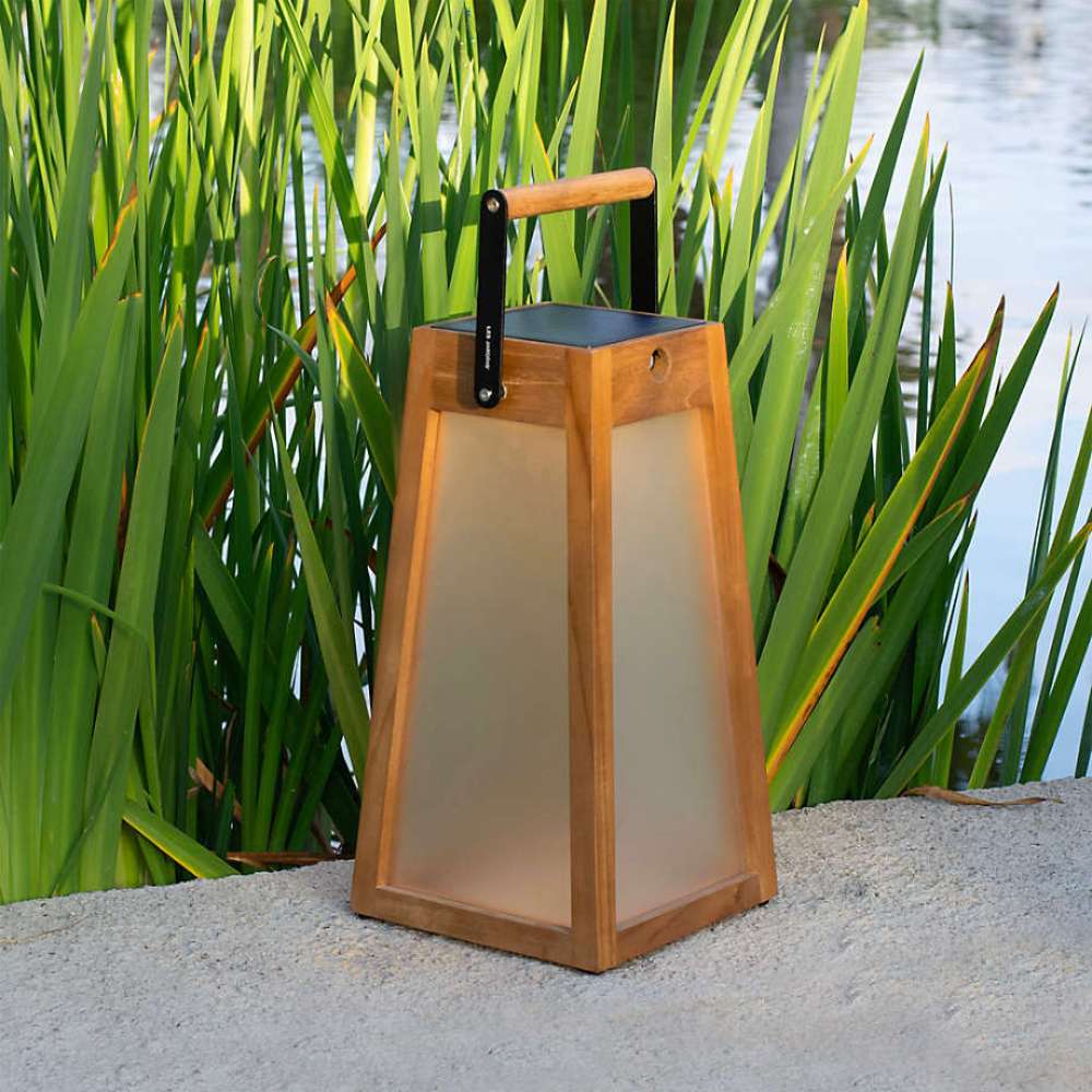 Weathered Teak Crate & Barrel Les Jardins Roam Teak LED Outdoor Solar-Powered Lantern 16" shown in a styled outdoor setting, a tapered teak lantern with frosted panels