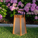 Weathered Teak Crate & Barrel Les Jardins Roam Teak LED Outdoor Solar-Powered Lantern 16" shown in a styled outdoor setting, cordless and carried by its aluminum and teak grip