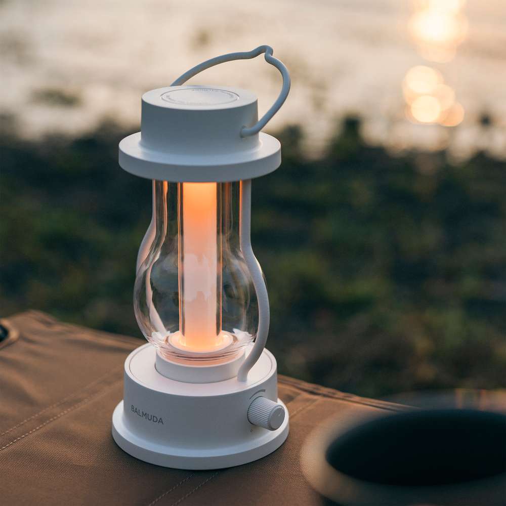 White Crate & Barrel Balmuda LED Rechargeable Outdoor Lantern shown on a plain background, a lantern with a candle flicker setting from 1,600K to 3,000K