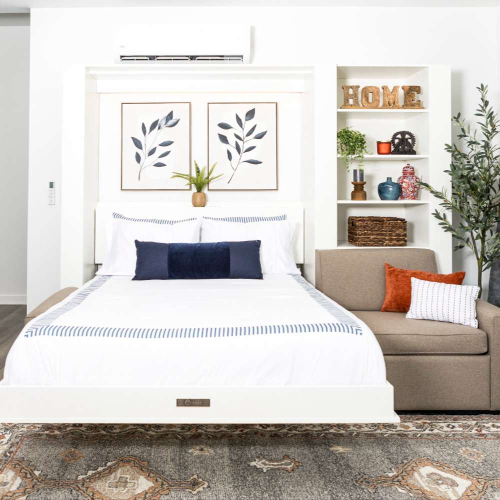 White Inovabed Wall Bed with Extended Sofa photographed room with the bed lowered, a navy pillow on the mattress and HOME letters on the bookcase shelves