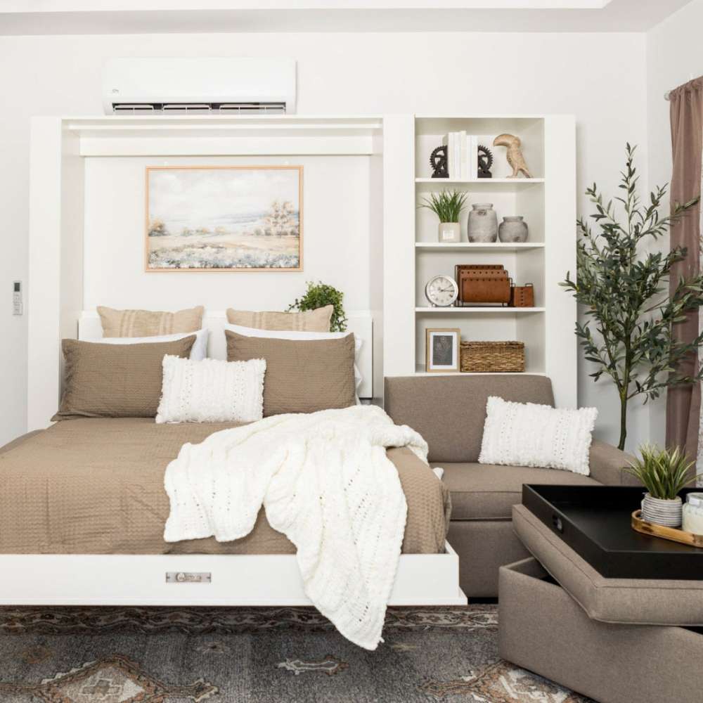 White Inovabed Wall Bed with Extended Sofa photographed room with the bed lowered, a throw across the mattress and an ottoman beside it