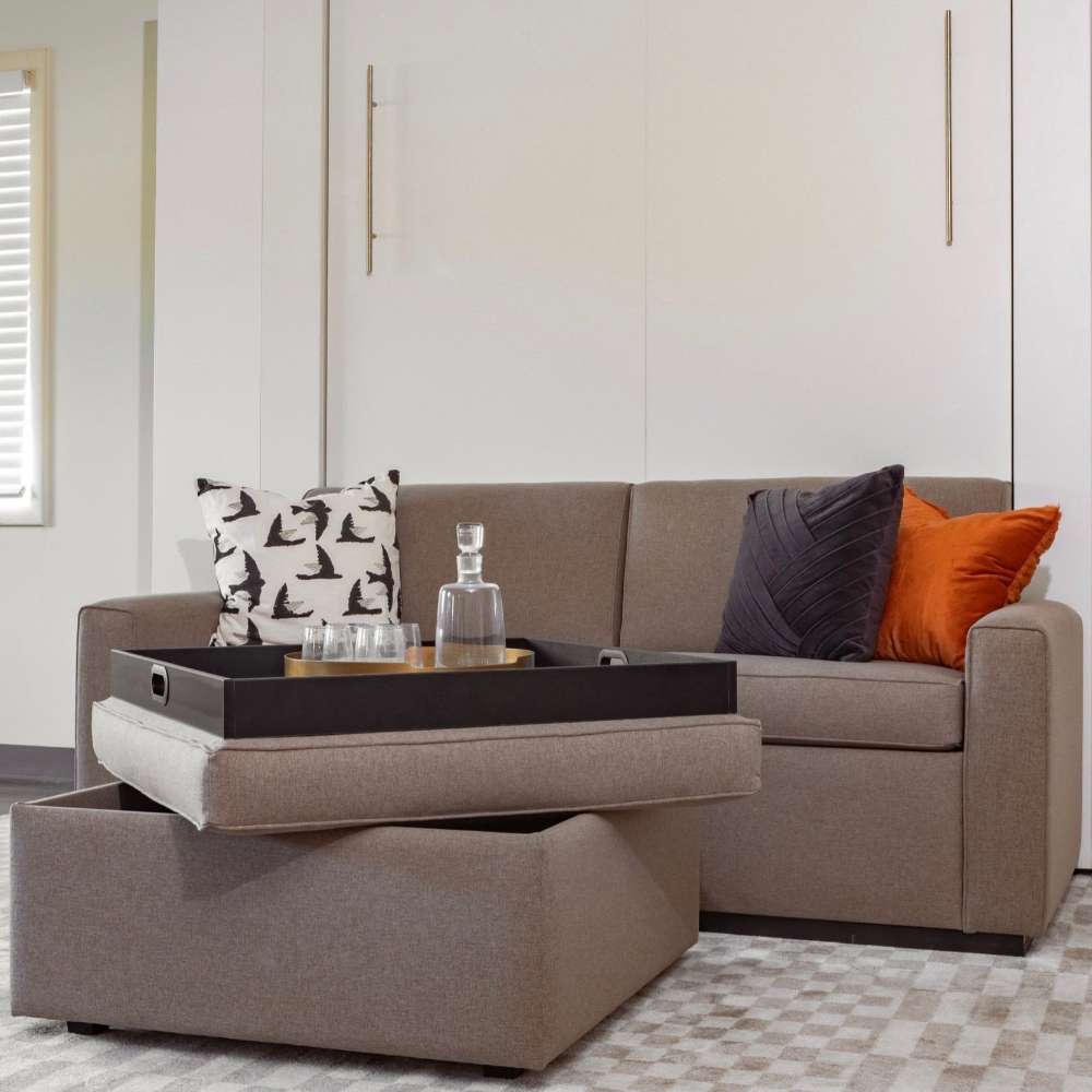 White Inovabed Wall Bed with Extended Sofa photographed room with the unit closed as a sofa, an ottoman with a serving tray and orange and navy pillows