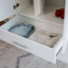 White Inovabed Wall Bed with Sofa and Wide Flex Cabinet in close-up with a Wide Flex Cabinet drawer pulled open on folded clothes, with red shoes on the shelf above