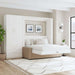 White Inovabed Wall Bed with Sofa and Wide Flex Cabinet opened in a bright room beside the Wide Flex Cabinet, with white bedding, a beige sofa base and two framed prints above the headboard