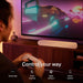 White Sonos Ray Sound Bar on a walnut console below a television showing a neon video game as a person holds a controller, with the words Control your way and icons for Sonos App, Touch Controls, Apple AirPlay 2 and Direct Control