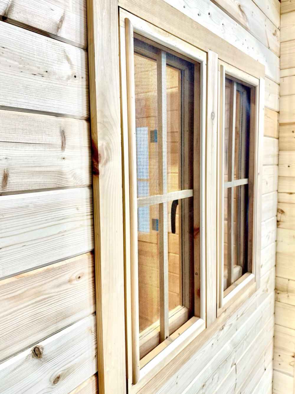wood-framed window exterior of a Sawmill Structures BlueWater Bungalow 160 Garden Room, set against horizontal pine siding