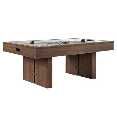 Woodgrain Crate & Barrel Air Hockey Table at a three quarter angle on a white background with the cream playing field, grey starburst print, two black strikers and an oval goal opening in the end panel