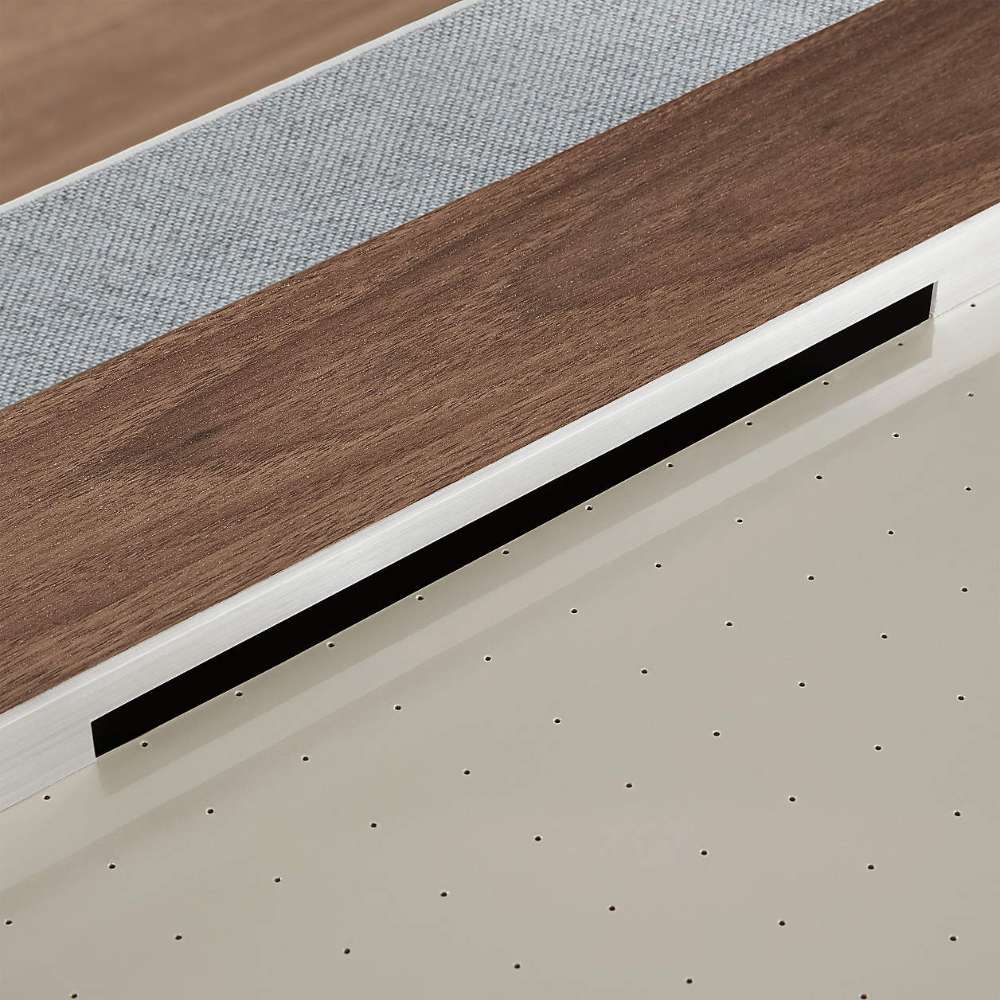 Woodgrain Crate & Barrel Air Hockey Table in tight close up on the cream playing field showing the grid of small air holes and the narrow black goal slot at the base of the rail