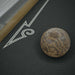 Woodgrain Crate & Barrel Skee-Ball Home Arcade Premium in close up on a single speckled ball resting on the black lane next to a painted white arrow
